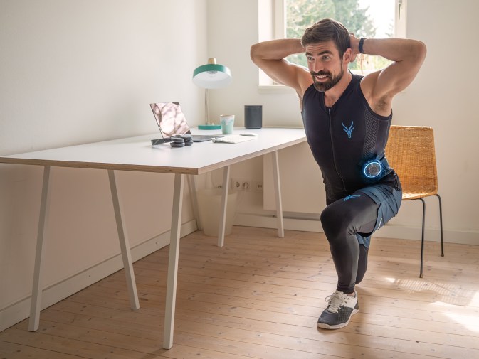 Ein Mann nutzt den EMS Anzug von Antelope zur Dehnung der Rückenmuskulatur im Home Office.