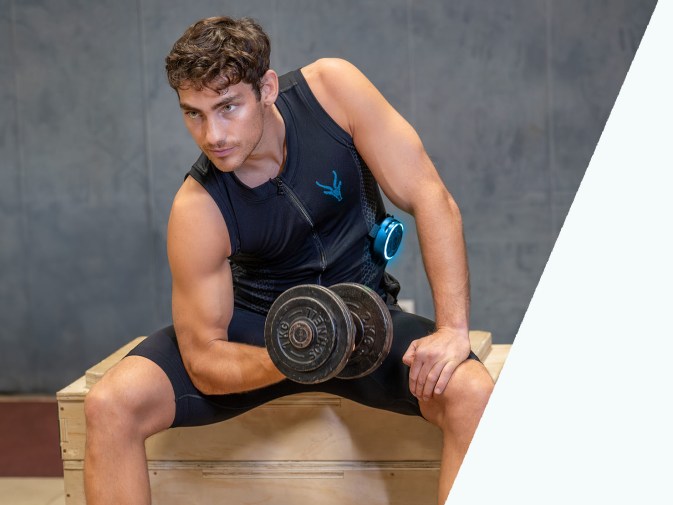 Ein sportlicher junger Mann, trainiert mit Gewichten. Er trägt das EMS Tank Top von Antelope.