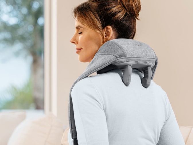 Junge Frau verwendet das Nacken-Massagegerät MG 154 an ihrem Nacken