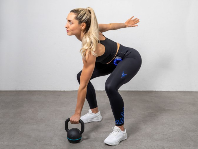 A fit woman is working out with a kettlebell. She's wearing the EMS High Waist Leggings from Antelope.