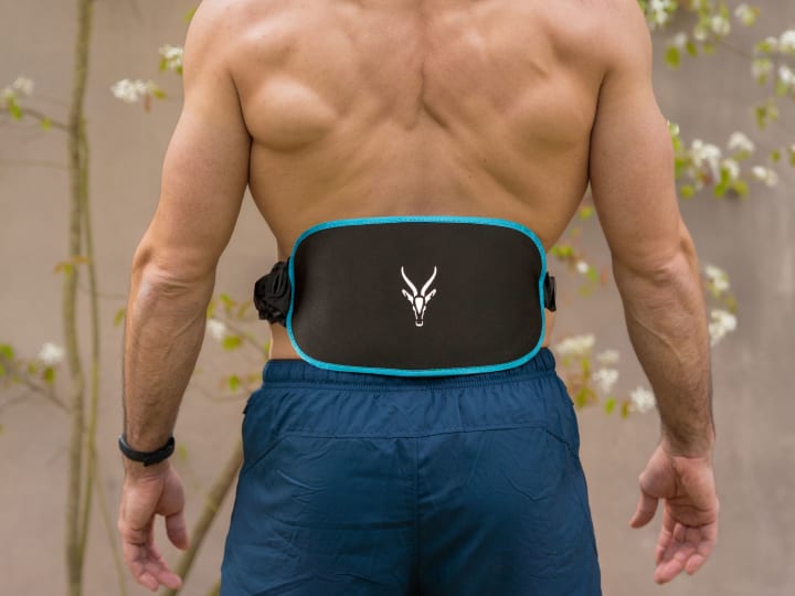 The back of an athletic man wearing the Corefit 2 EMS belt can be seen.
