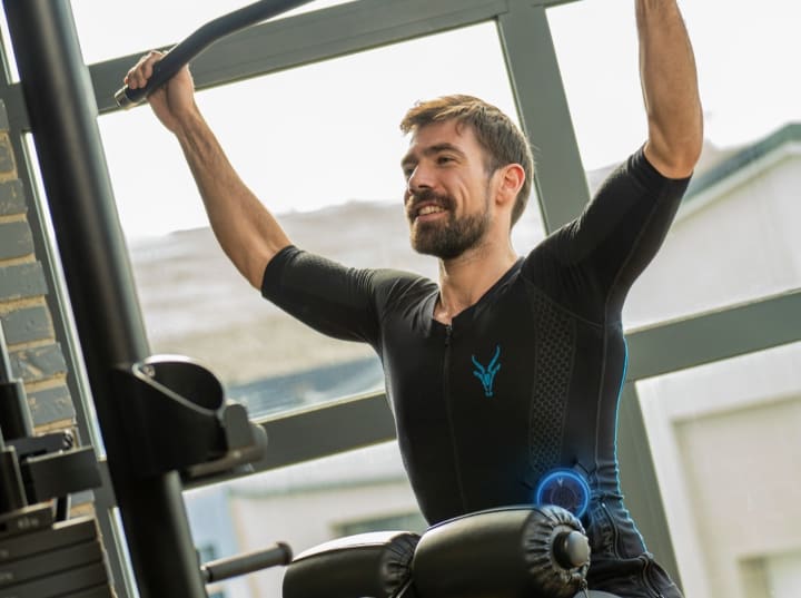 A man performs lat pulldowns on the cable machine wearing the Antelope EMS shirt at the gym.