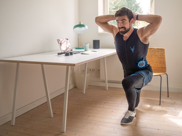 Ein Mann nutzt den EMS Anzug von Antelope zur Dehnung der Rückenmuskulatur im Home Office.