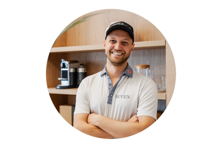 Ein Portrait von Tim Ruth. Er hat die Arme verschränkt und lächelt in die Kamera.