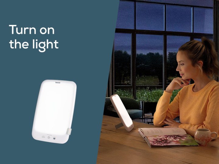 Homepage Teaser "Switch on the daylight"; Young woman sits in dark room with TL 35 daylight lamp