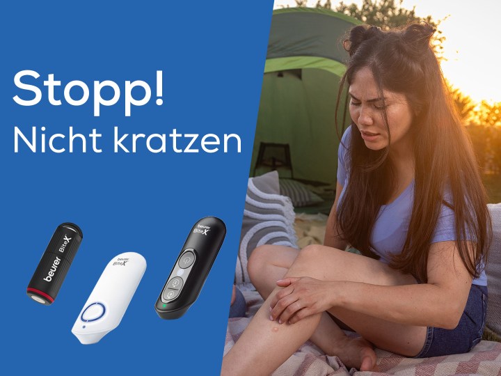 Junge Frau sitzt draußen auf einer Decke vor einem Zelt und kratzt sich am Bein nach einem Insektenstich