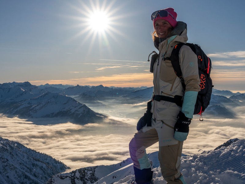 Ein Bild von Marina in dicker Winterkleidung. Hinter ihr ist eine Landschaft mit verschneiten Bergen.