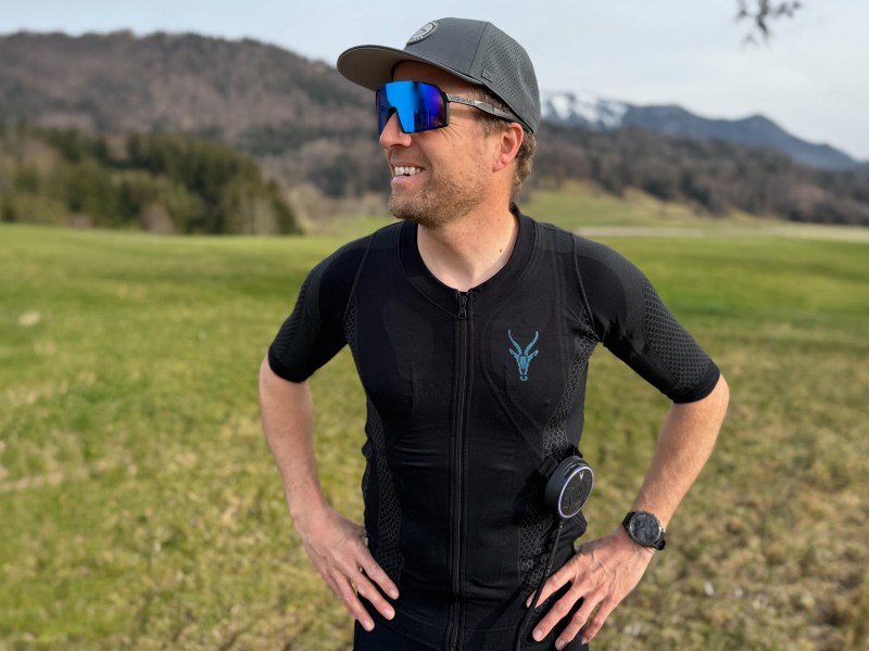 Ein Bild von Willi im EMS-Anzug von Antelope vor einer grünen Wiese. Er trägt eine Sonnenbrille und eine Kappe.