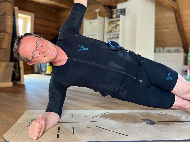 Emiljano im EMS Anzug, wie er einen Side-Plank zuhause ausführt.