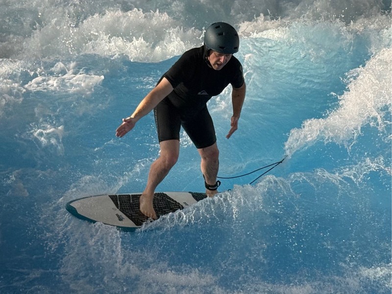 Emiljano surft auf einer Welle mit einem Surfboard