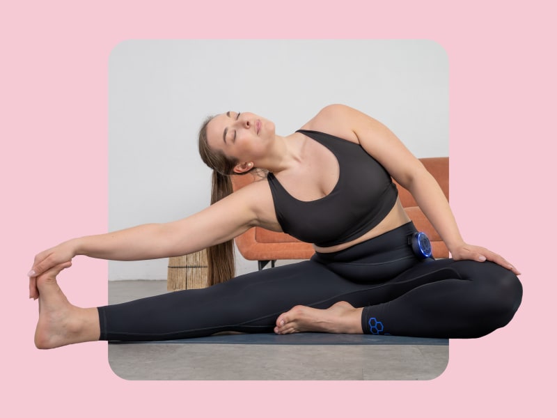 Woman wearing the Antelope EMS High Waist Leggings with Booster, performing a lateral stretch on a mat, showcasing flexibility, wearing comfort and freedom of movement during stretching.