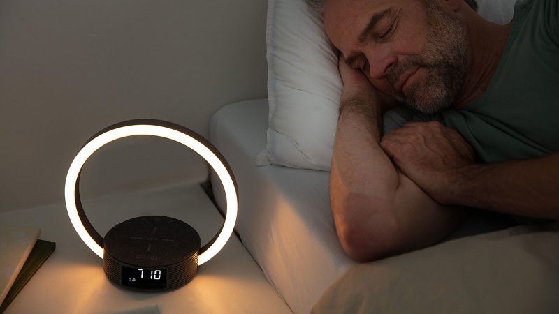 Mann schläft im Bett, neben ihm auf dem Nachttisch steht der Tageslichtwecker WL 65