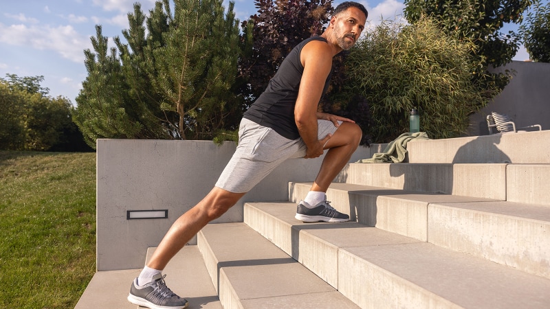 Mann dehnt seine Beine auf einer Treppe