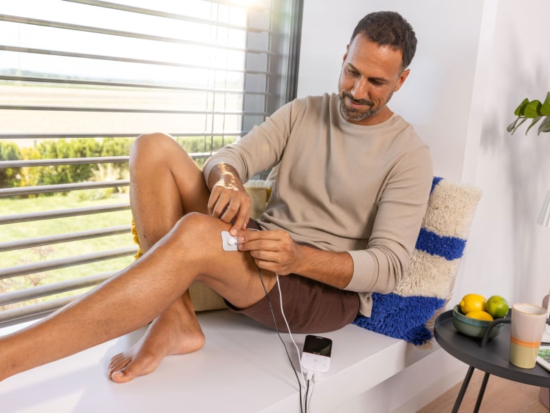 Ein Mann verwendet das Beurer EM 49, die an seinem Knie angebracht sind.