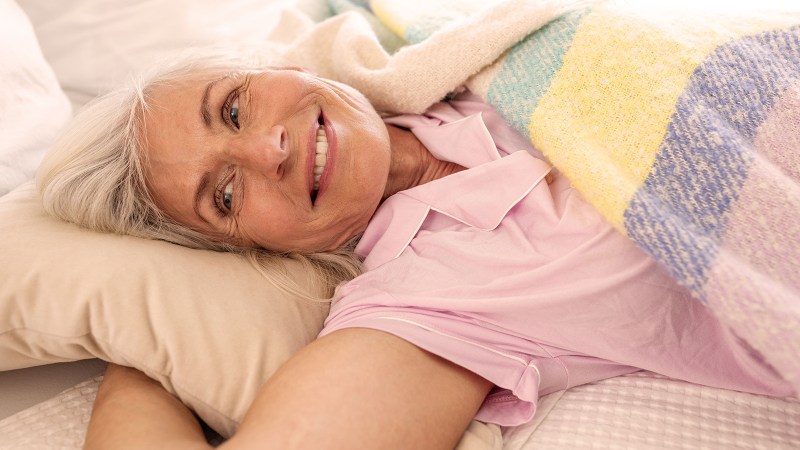 Frau liegt im Bett und lächelt