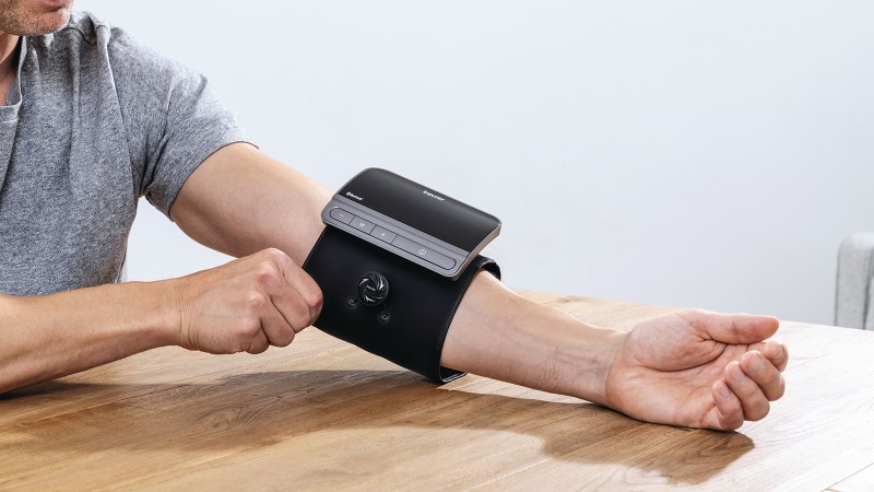 A man fits the tubeless easyLock cuff of the Beurer BM 81 to his upper arm and tightens it.