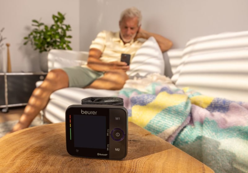 Mann sitzt auf dem Sofa mit dem Smartphone in der Hand. Im Vordergrund ist ein BC 54 zu sehen.