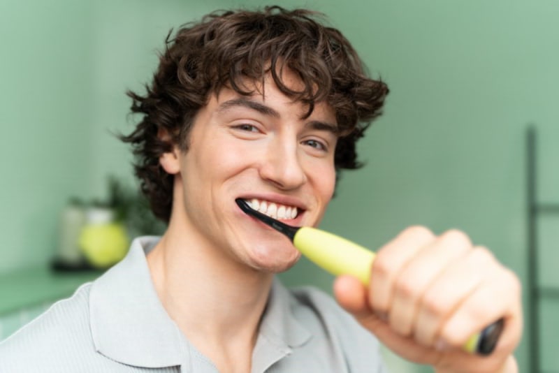 A young man brushing his teeth with the Beurer SC 50 electric toothbrush.
