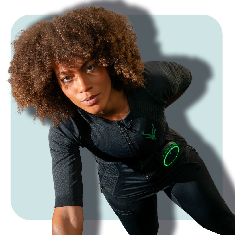 Eine junge Frau führt einen Liegestütz mit einer Hand aus. Sie trägt das EMS-Shirt von Antelope. ihre Trainingsergebnisse in der App. Eine junge Frau führt einen Liegestütz mit einer Hand aus. Sie trägt das EMS-Shirt von Antelope. ihre Trainingsergebnisse in der App.