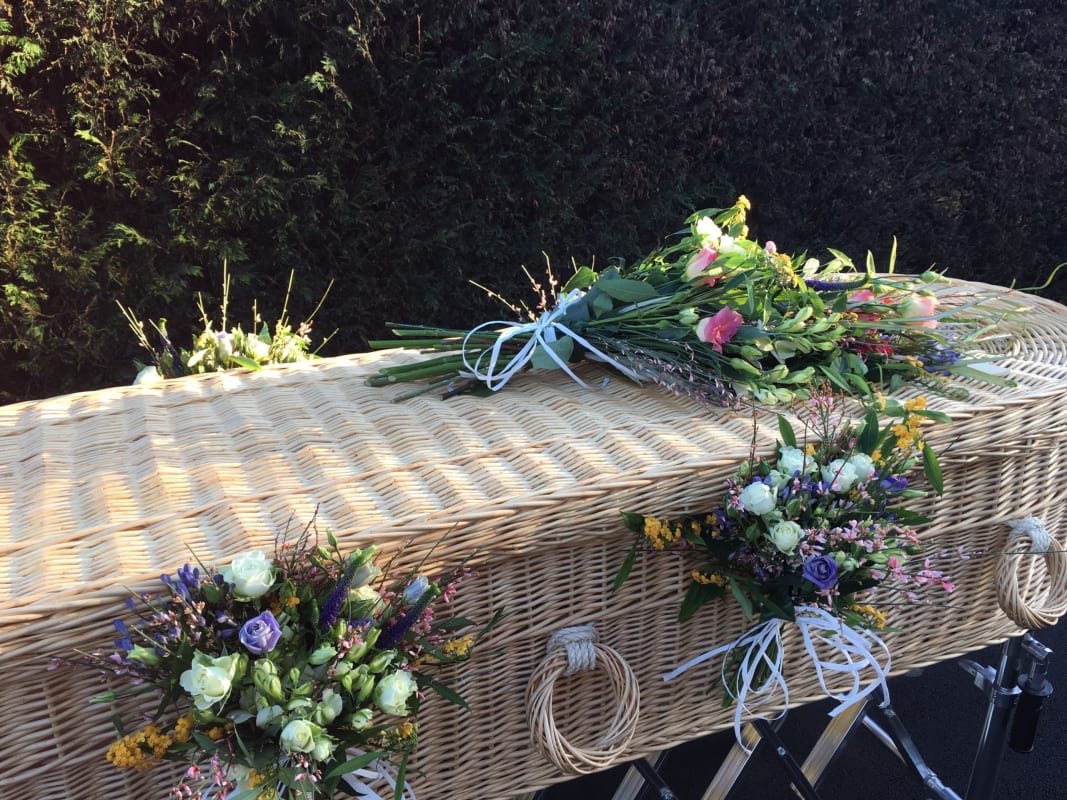 A wicker coffin decorated with flowers by the team at Full Circle Funerals