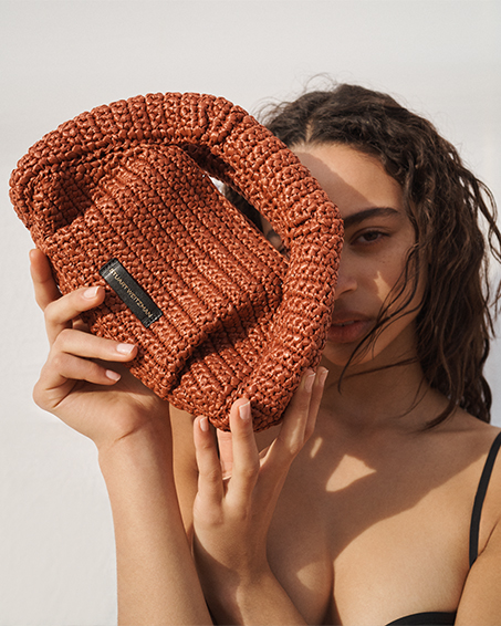 Model holds Stuart Weitzman - The Moda Mini Raffia Top-Handle Bag