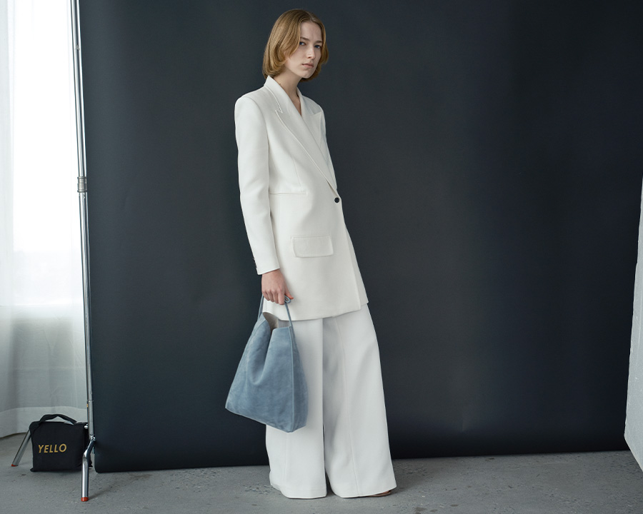 Model Wears Khaite - Jacobson One-Button Jacket, Bacall Straight Leg Pants, and Frida North-South Calfskin Tote Bag