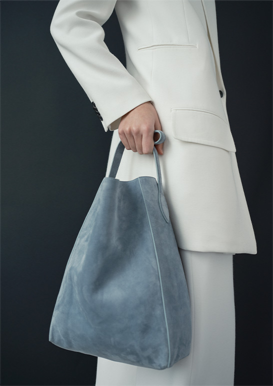 Model Wears Khaite - Jacobson One-Button Jacket, Bacall Straight Leg Pants, and Frida North-South Calfskin Tote Bag