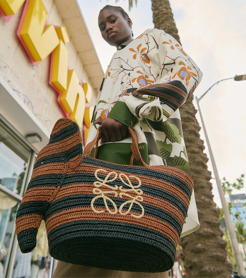  Model carries Loewe - Small Elephant Basket Bag in Striped Raffia