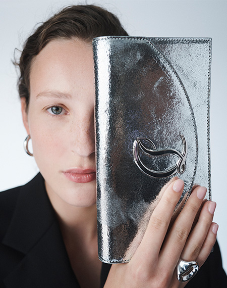 Model holds Christian Louboutin - Loubi54 Metallic Leather Clutch Bag