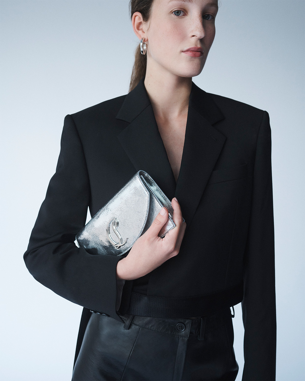 Model wears Christian Louboutin - Loubi54 Metallic Leather Clutch Bag