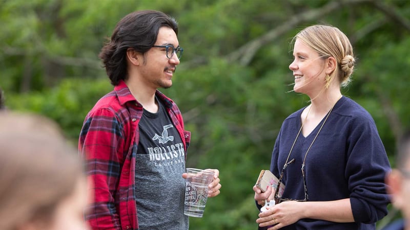 Male and female student stodd outside college campus looking happy and having a discussion