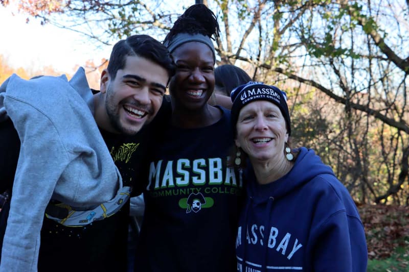 Students outside campus smiling toward camera