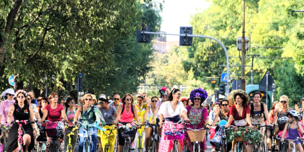 A photo of a group of fancy women riding bicycles.