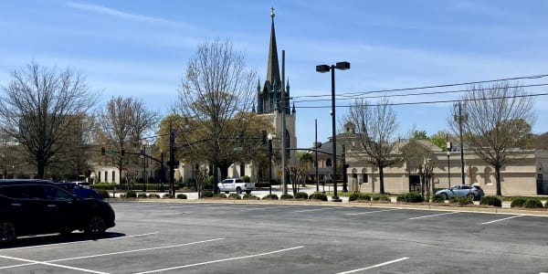 A photo of a mostly-empty parking lot and a church steeple in the distance.