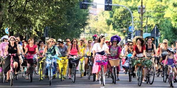 A photo of a group of fancy women riding bicycles.