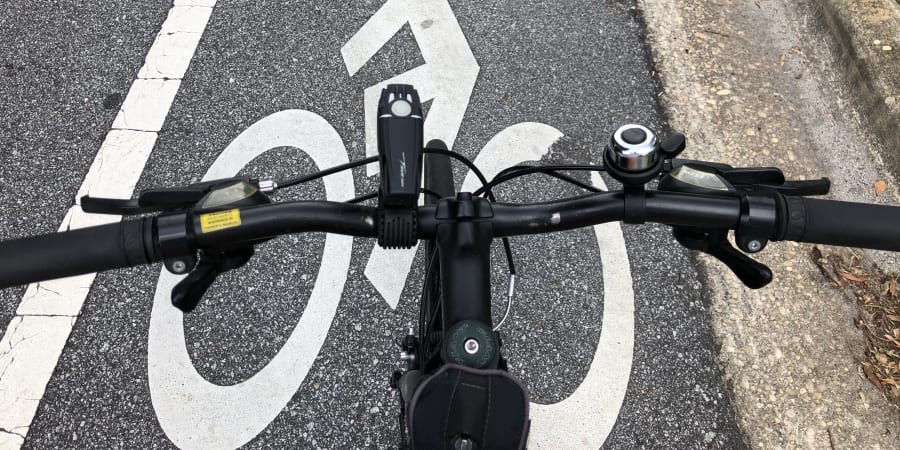 A photograph of a bicycle handlebars over a bicycle lane marking.