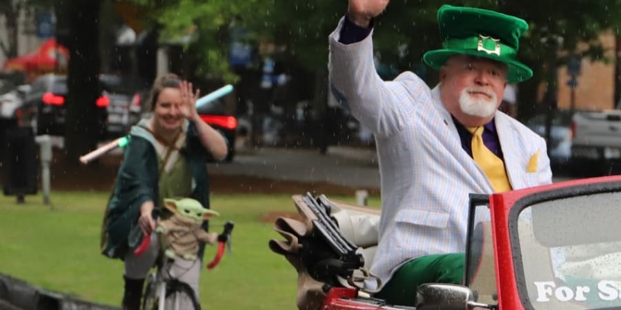 A photo from a parade with a person dressed as a Jedi on a bicycle.