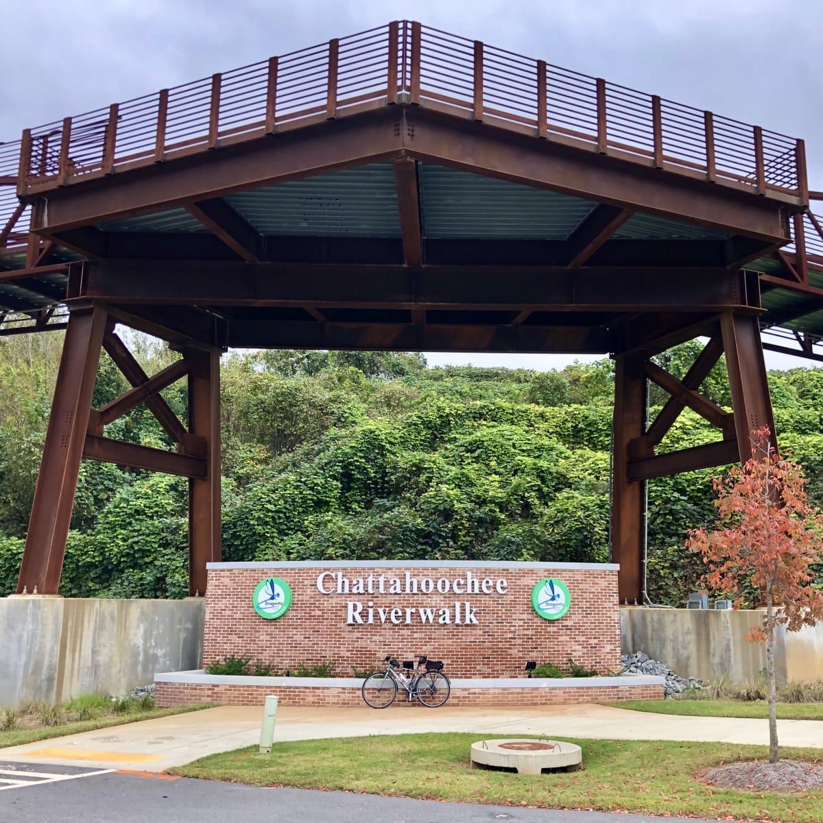 A photo of my bicycle in front of a sign for "Chattahoochee Riverwalk" and under a pedestrian bridge.