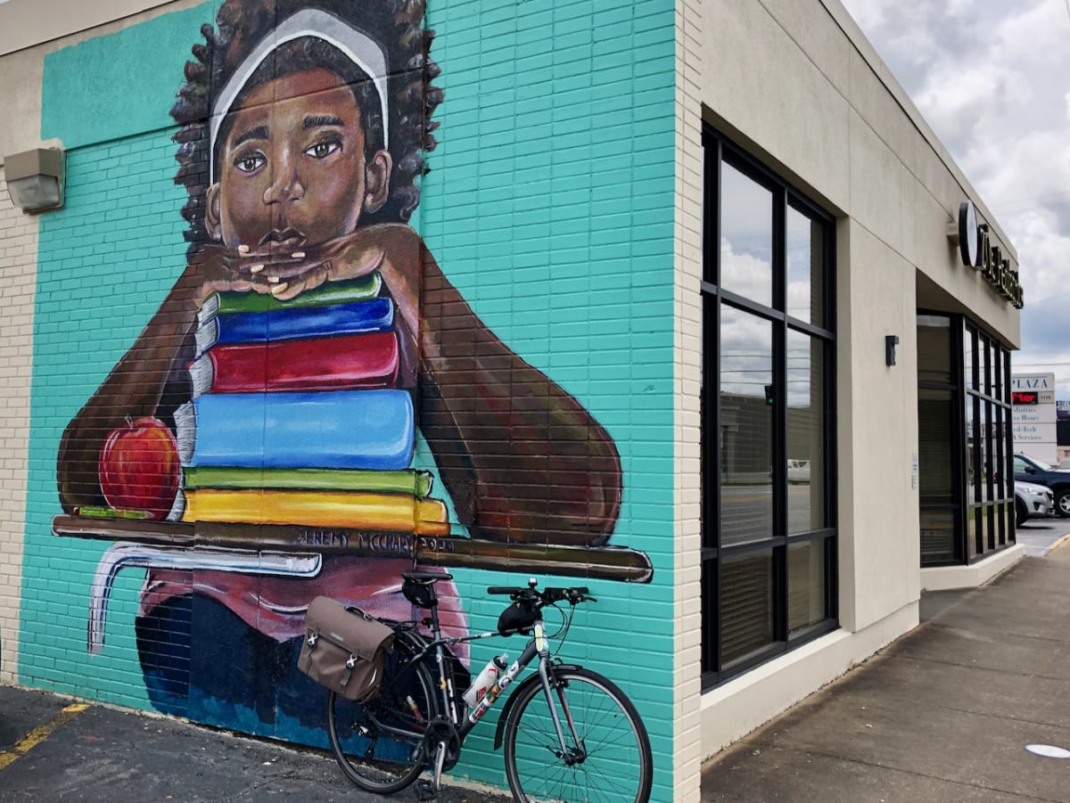 A photo of my bicycle in front of a mural with a painting of a student in a desk.