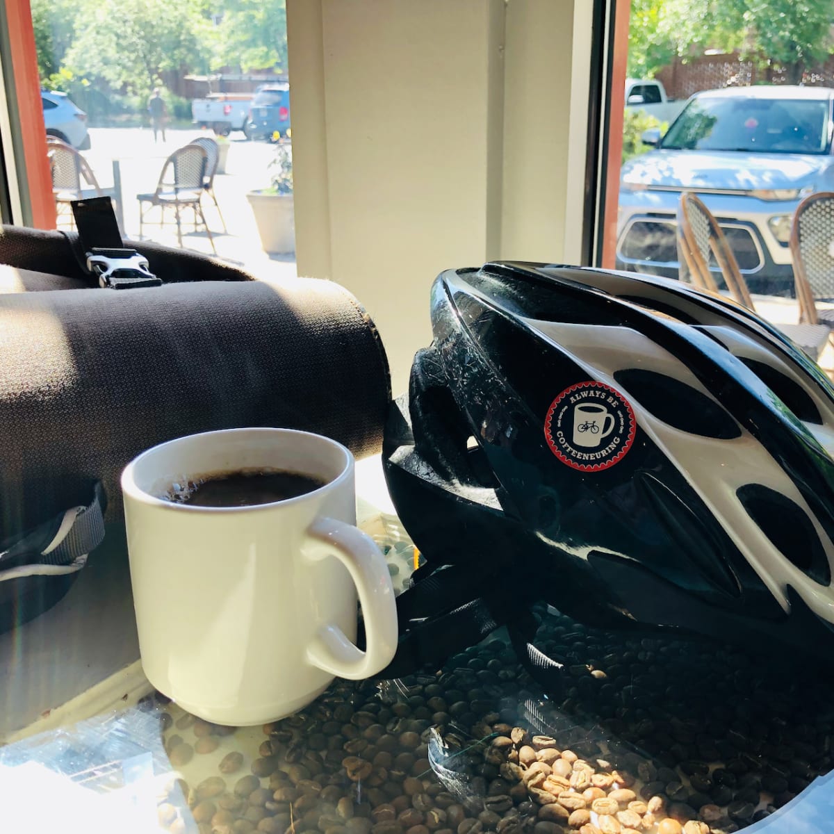 A photo of a coffee cup on a table beside a bicycle helmet.