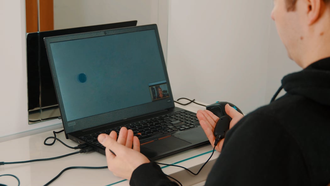 Client in an online EMDR session using a laptop and remote tactile BLS buzzers