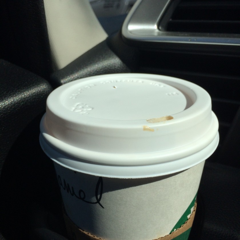 Dirty chai latte in a paper starbucks cup sitting in a car cup holder