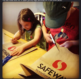 Kids cutting paper grocery bags at the dining table