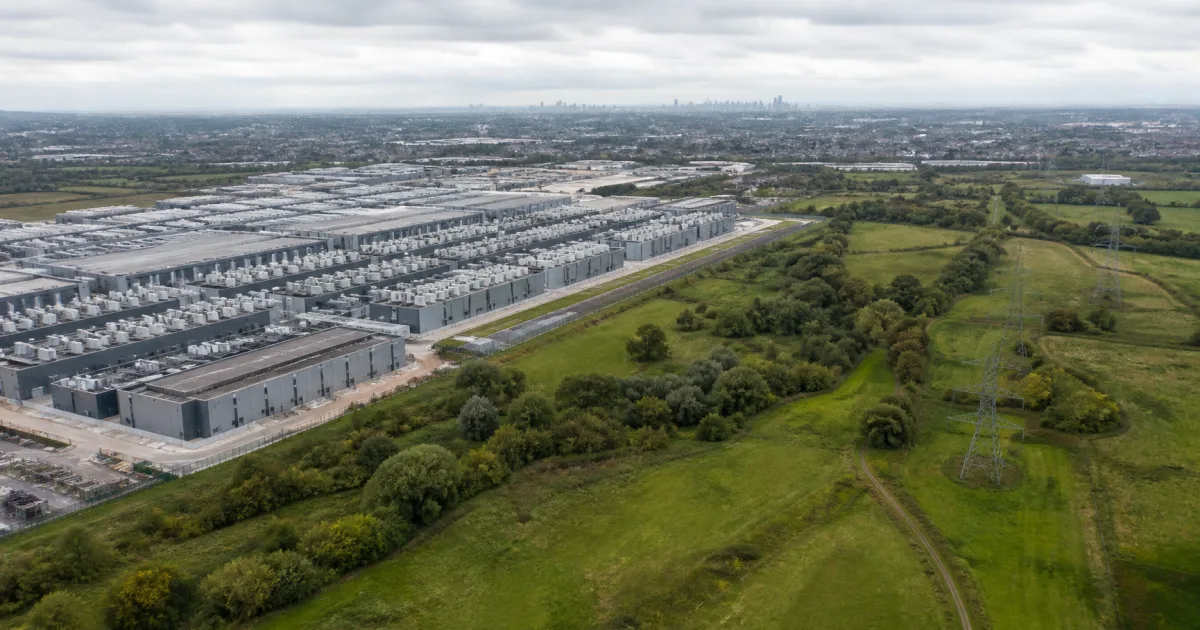 Large data centre campus beside green fields and trees on the edge of London