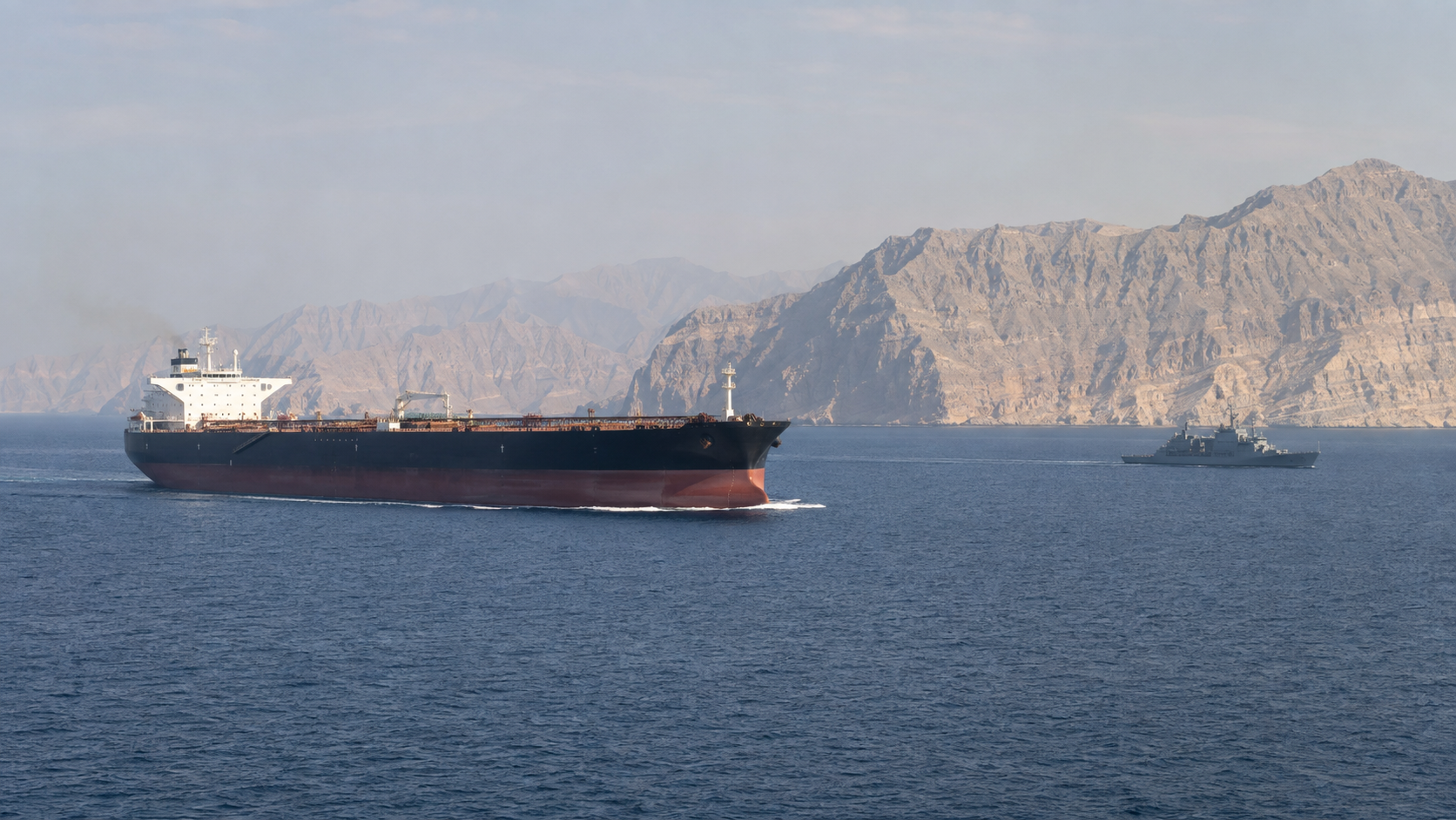 Oil tanker and naval patrol vessel navigating near the Strait of Hormuz