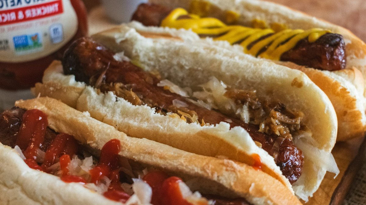 A couple of hot dogs sitting on top of a wooden cutting board.
