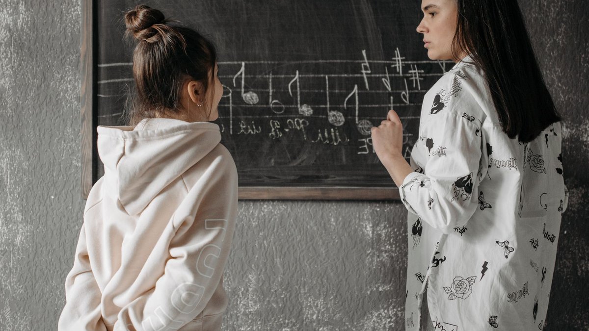 A teacher instructs a student in musical notation in a classroom setting.