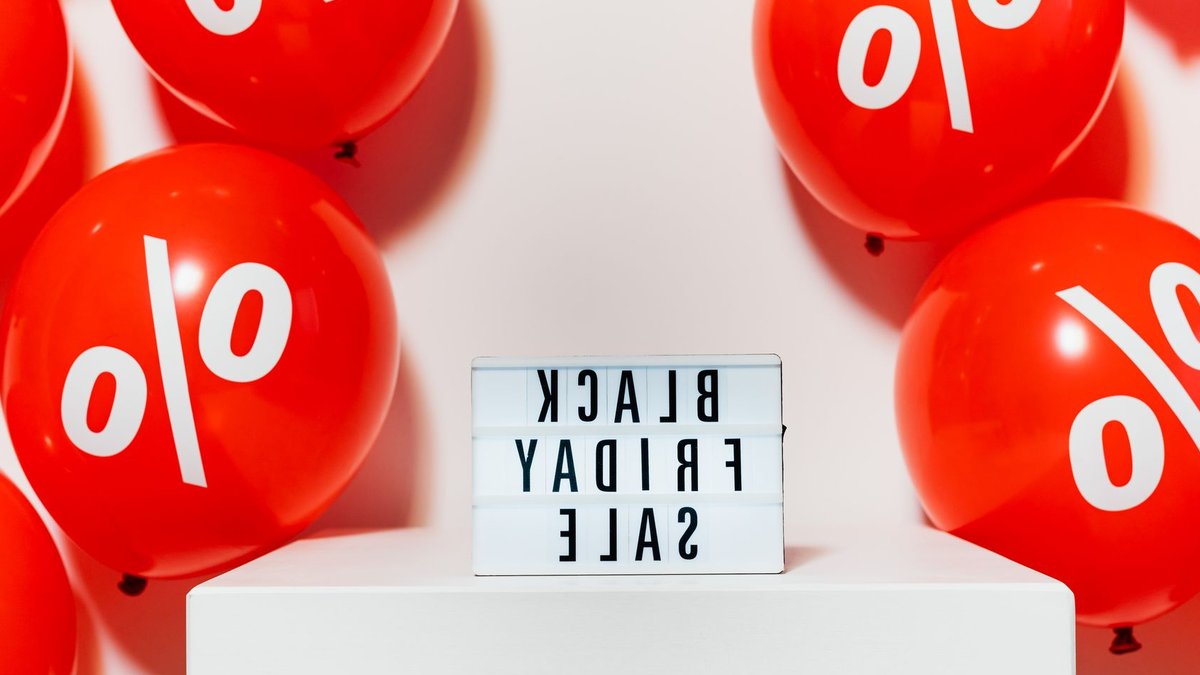 Households feel inflation higher than reported Red balloons with percentage symbols flank a Black Friday Sale sign, creating a festive shopping atmosphere.