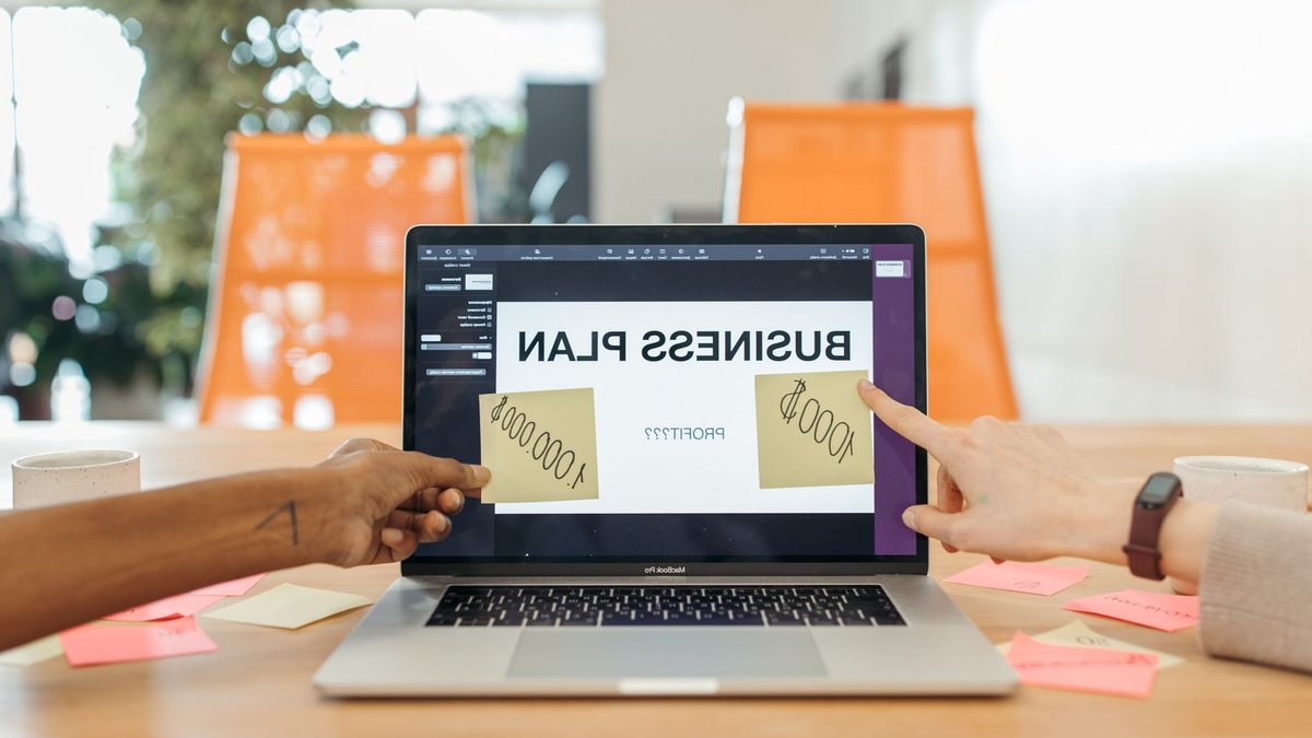 LSL Property profits rise on franchise margin boost Two professionals strategizing a business plan on a laptop with sticky notes and profit goals.