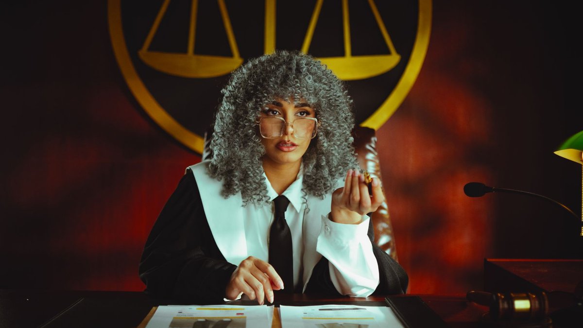 Portrait of a judge in a courtroom with the scales of justice emblem in the background.